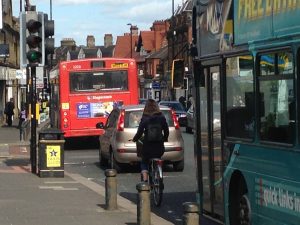 Picture of a lady cycling on Gosforth High Street between two buses