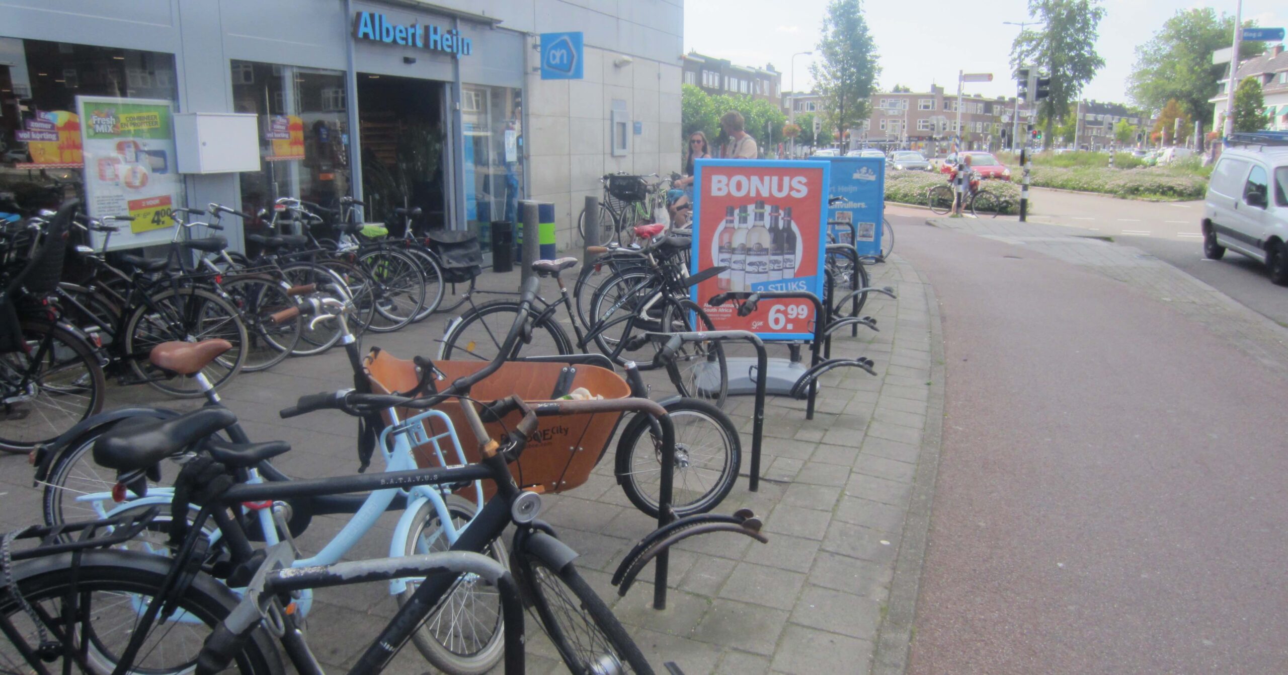 A local Dutch supermarket showing cycle parking for customers and a traffic-free cycle path