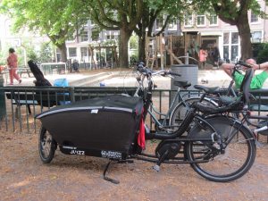 Electric cargo bike with child seat by a park in Amsterdam