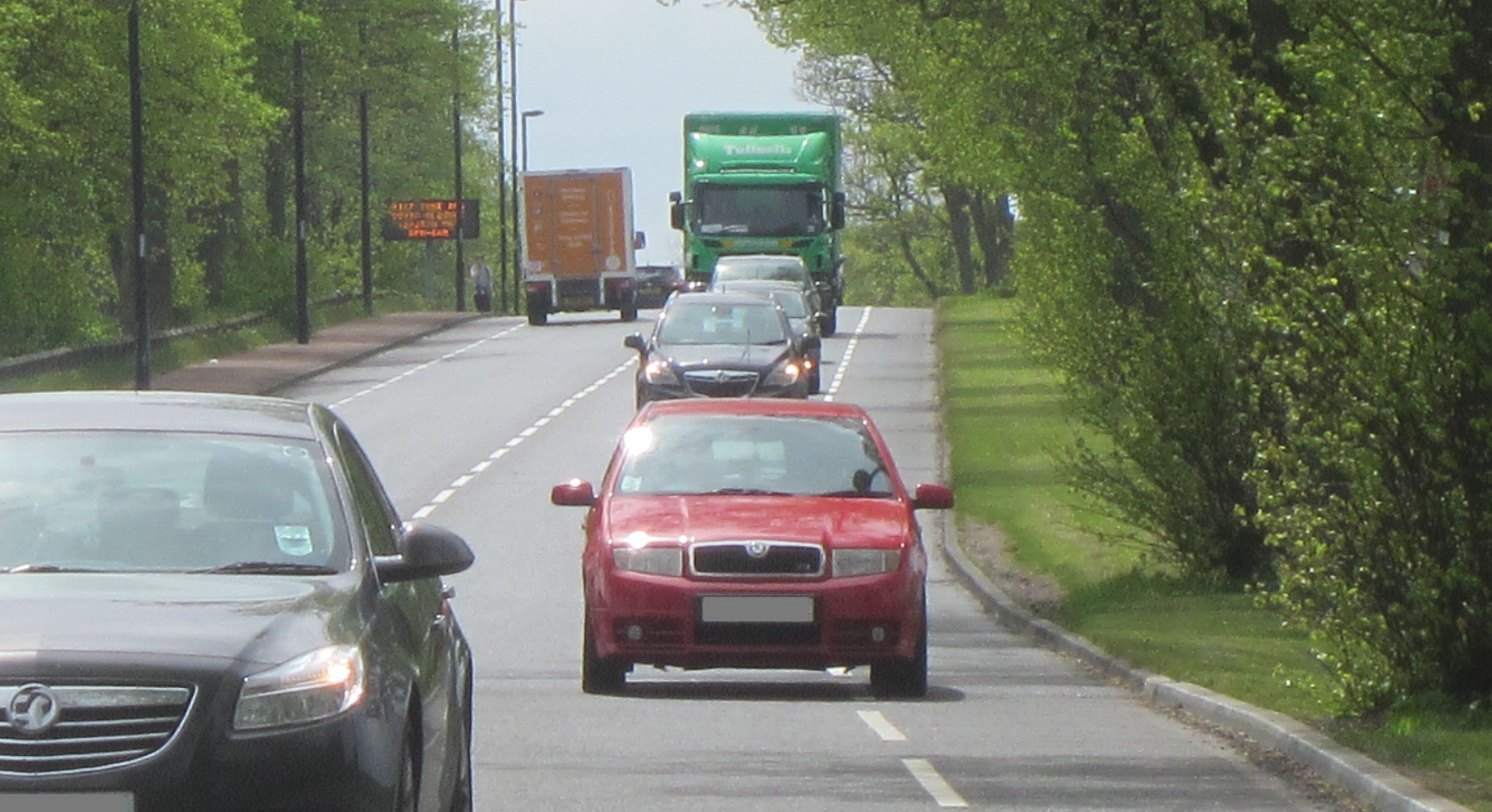 Red car driving in the cycle lane on Grandstand Road