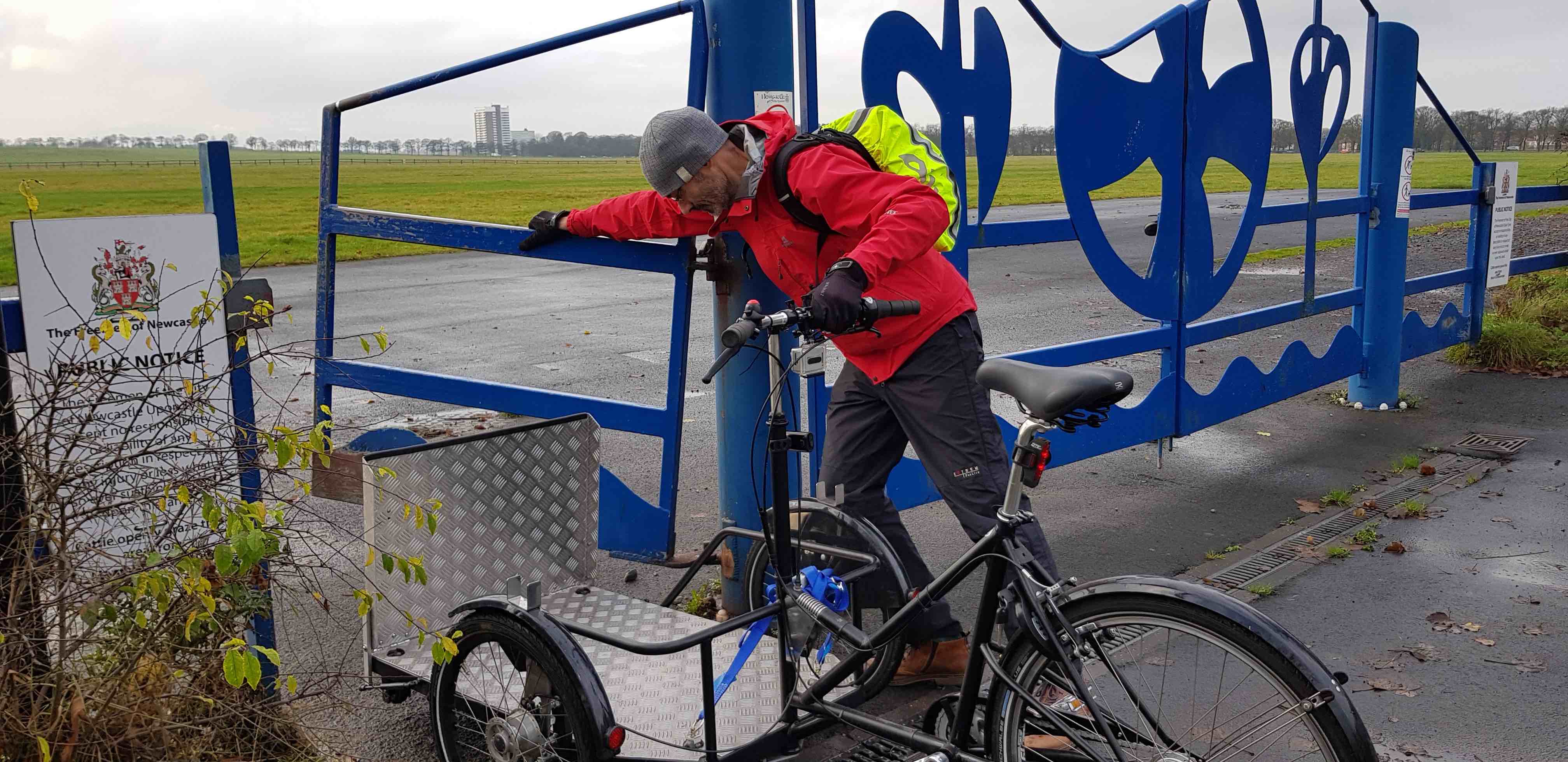 Picture of an adapted cycle rider struggling to open the gate to the Town Moor.