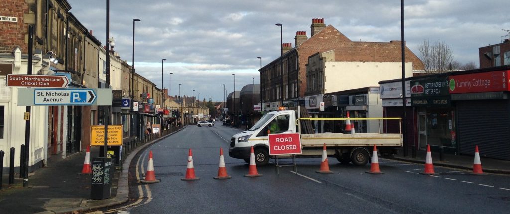 Picture of Gosforth High Street looking north from Hawthorn Road, with the road blocked by cones for the Remembrance Sunday parade.