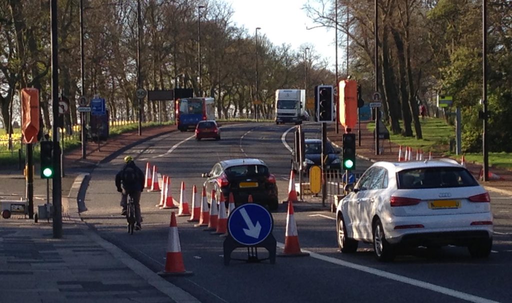 Picture of roadworks by Little Moor with cones and someone cycling inside the cones.