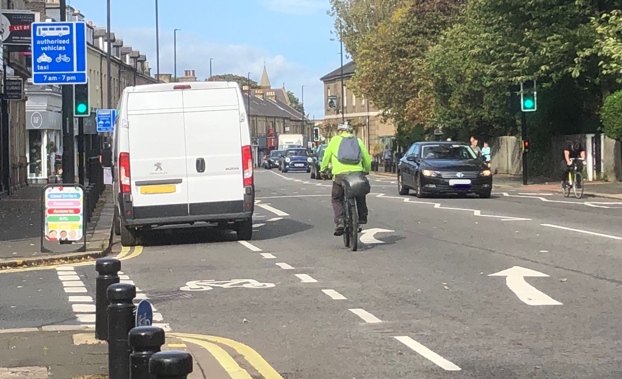 Man on a bicycle overtaking a van parked in the bus lane on Gosforth High Street